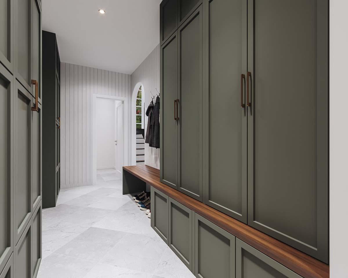A modern hallway with olive green cabinets, a wooden bench, and white paneled walls. Coats hang near a doorway, and shoes sit below the bench.