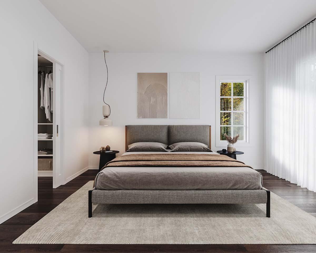 A modern bedroom with a gray bed, artwork, and a window with a view of trees. A small black side table sits next to the bed.