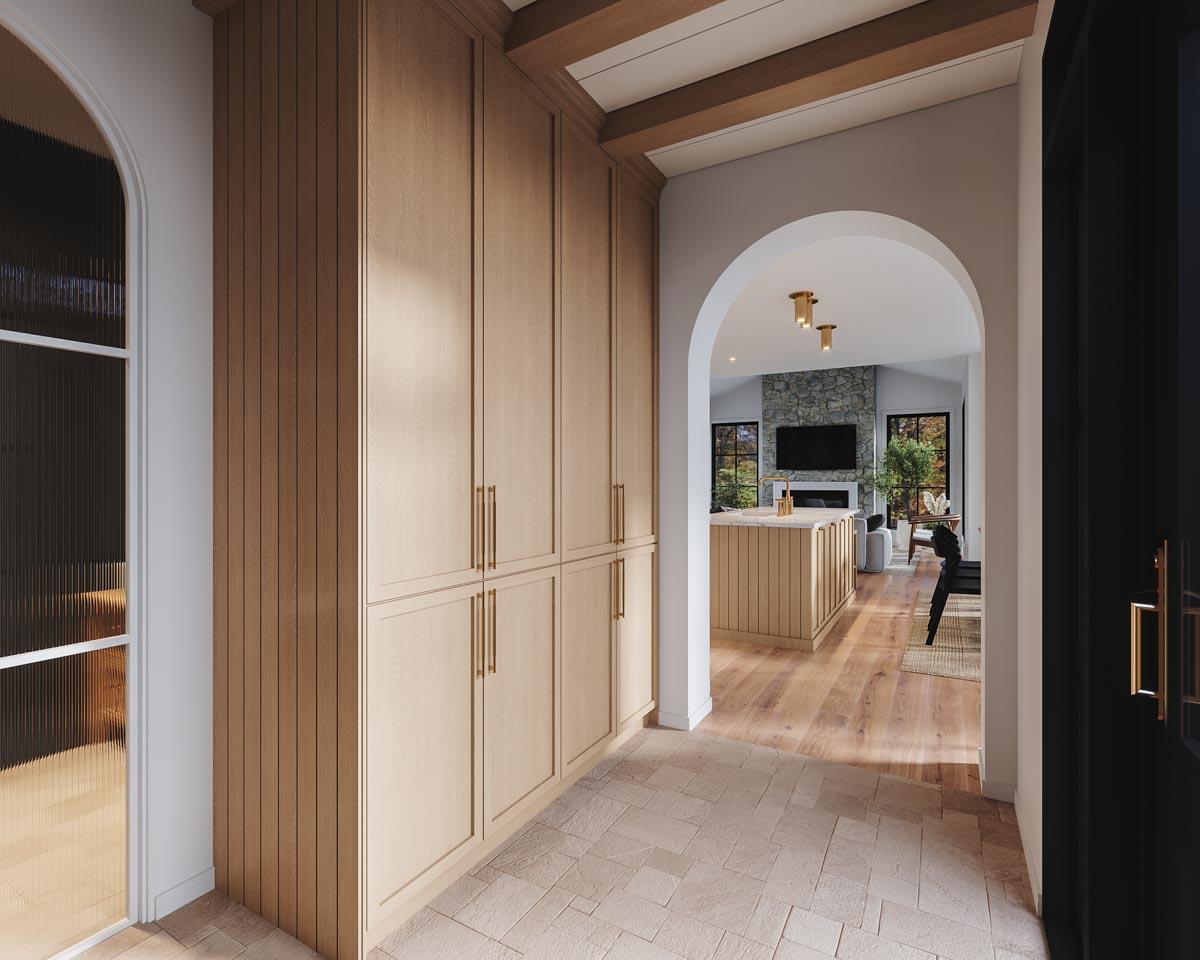 Interior view of a house showcasing wood cabinetry, arched doorway, stone fireplace, and kitchen island.
