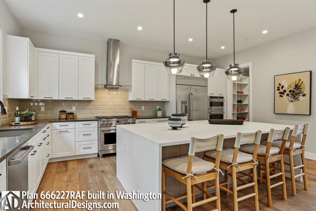 Modern kitchen with white cabinetry, large island with seating, stainless steel appliances, and subway tile backsplash.