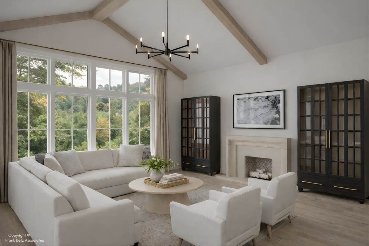 Living room with vaulted beamed ceiling, large grid windows, sectional sofa, fireplace, and two display cabinets.