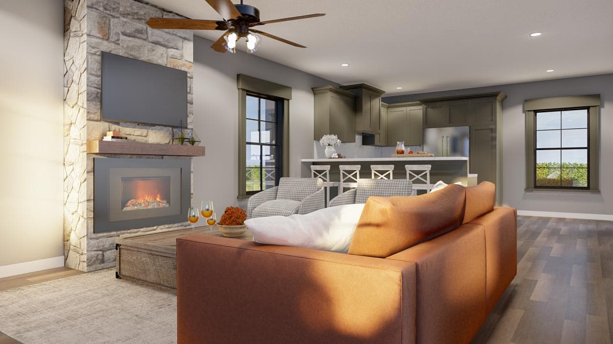Open concept living area with stone fireplace, television, kitchen island with bar stools, and seating area.
