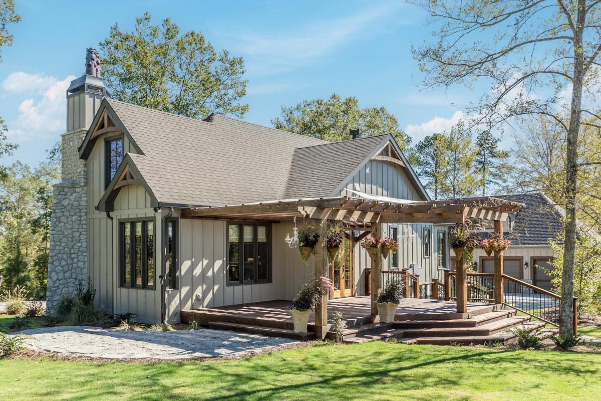 House plan exterior: Craftsman style, two stories, stone chimney, gabled dormers, and covered deck with pergola.