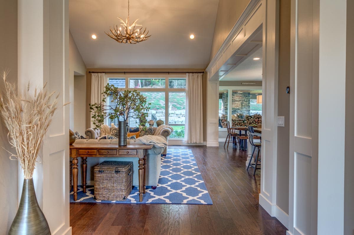 Interior view of a great room with vaulted ceiling, large windows, and an open layout leading to a dining area.