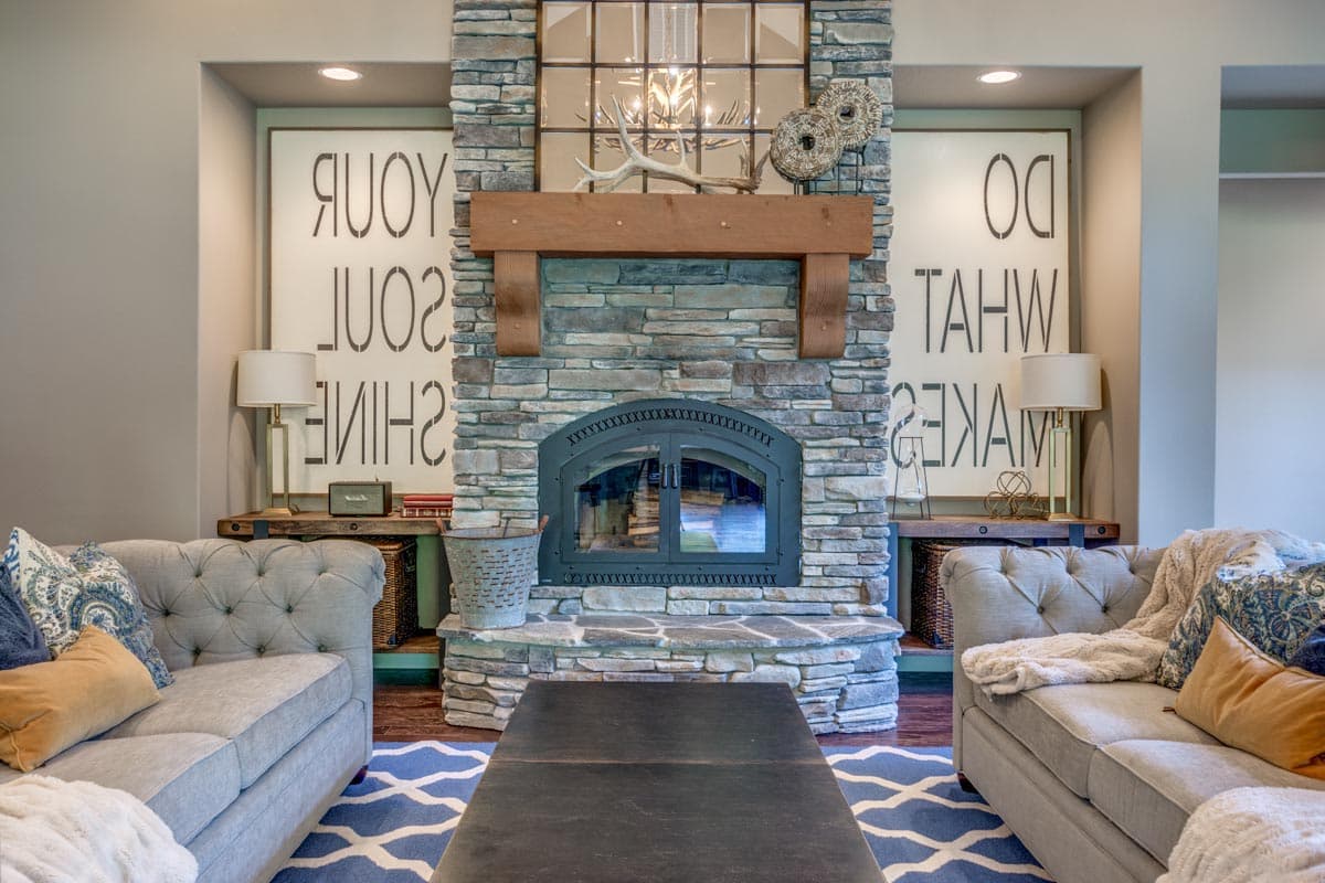 Living room with stone fireplace, wood mantel, arched glass doors, and symmetrical seating arrangements.