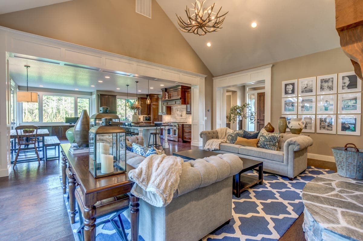 Interior view of open-concept living area with vaulted ceiling, fireplace, kitchen island, and dining area.