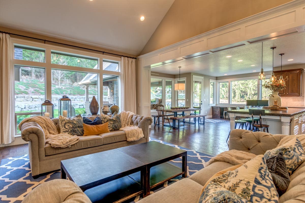 Great room with vaulted ceiling, large windows, open to dining area and kitchen with island.