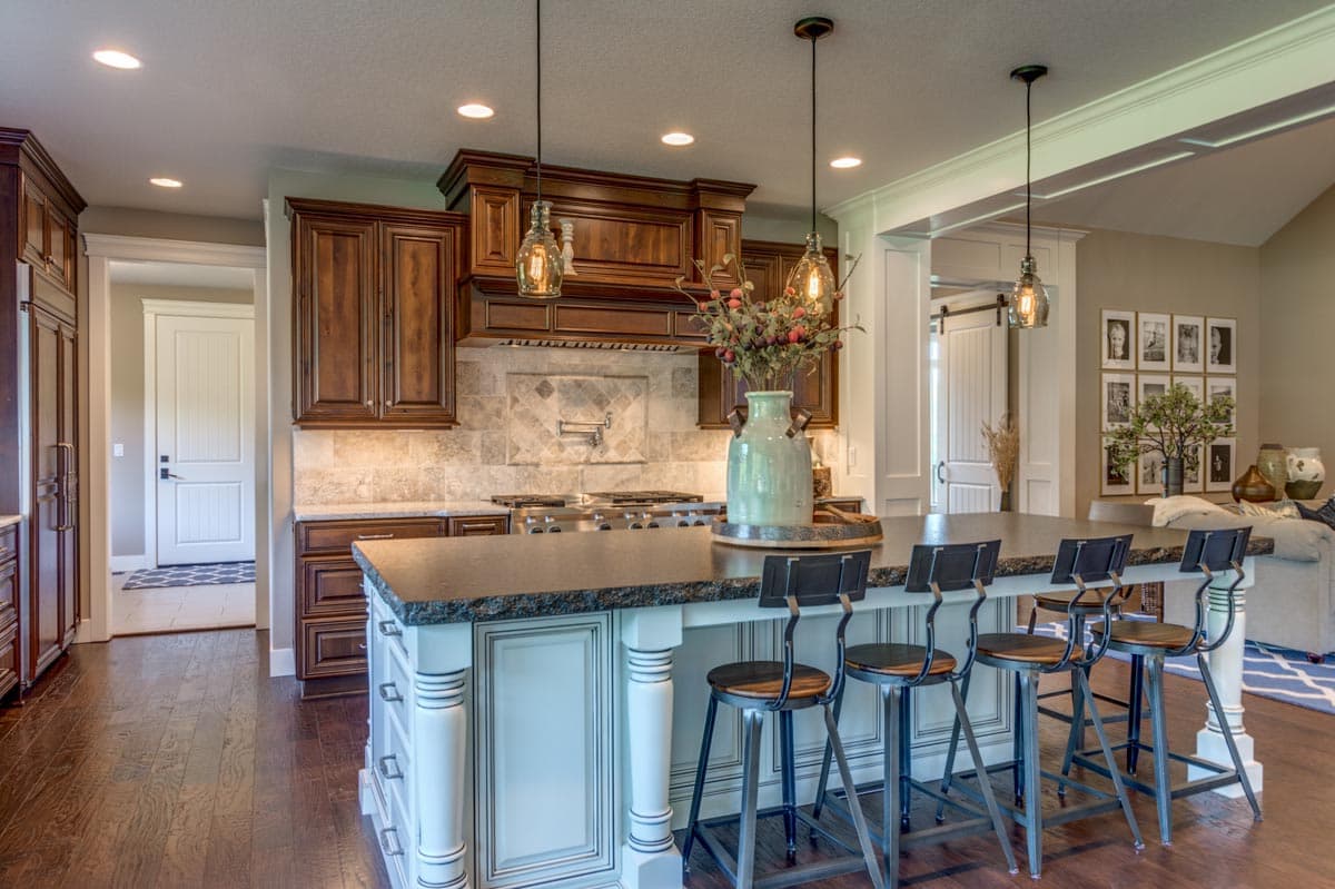 Kitchen interior featuring dark wood cabinetry, a large island with seating, pendant lights, and stainless steel appliances.