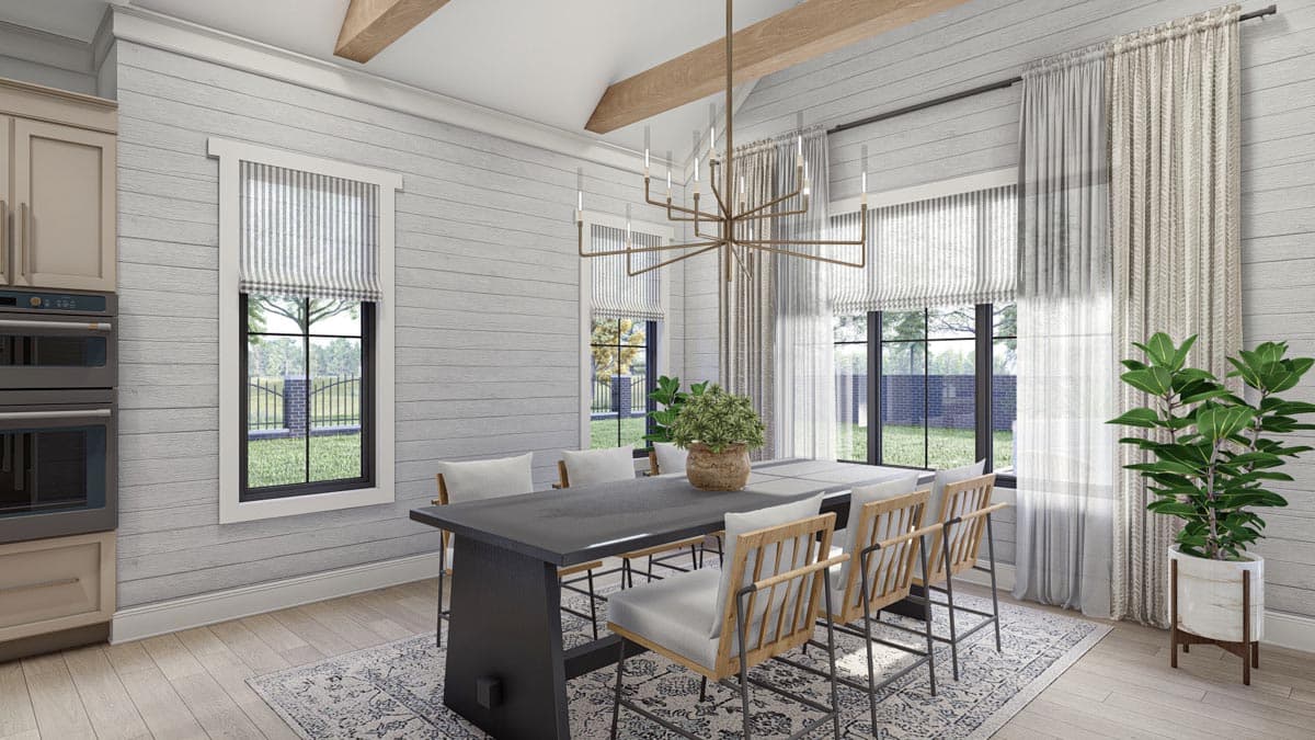 Dining room with vaulted beamed ceiling, shiplap walls, large windows, and a dark table with chairs.