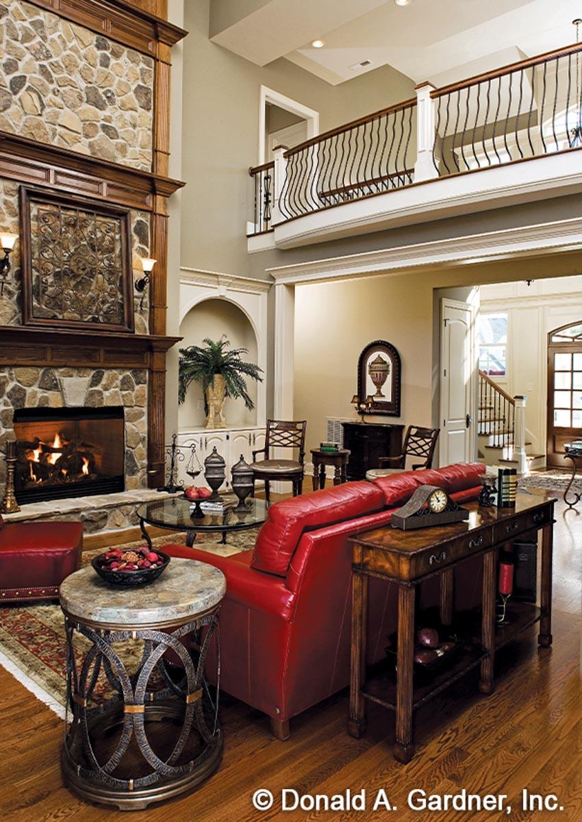 Living room with stone fireplace, red leather sofa, and open second-floor balcony.