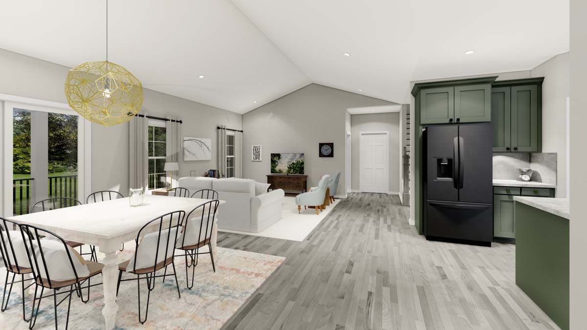 Open concept living area with vaulted ceiling, dining table, sectional sofa, fireplace, and kitchen with green cabinets and black refrigerator.