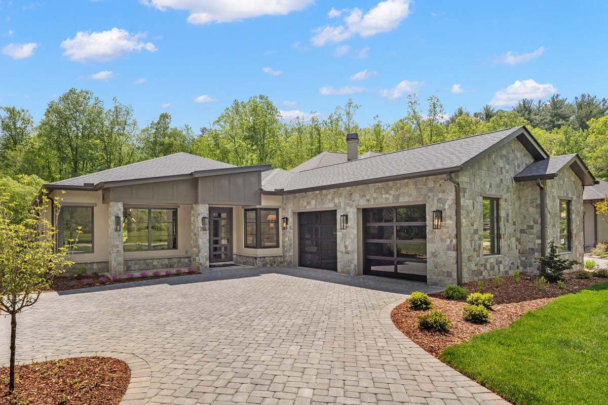 Modern ranch house plan exterior with stone facade, dual garage doors, and a covered entry with asymmetrical rooflines.