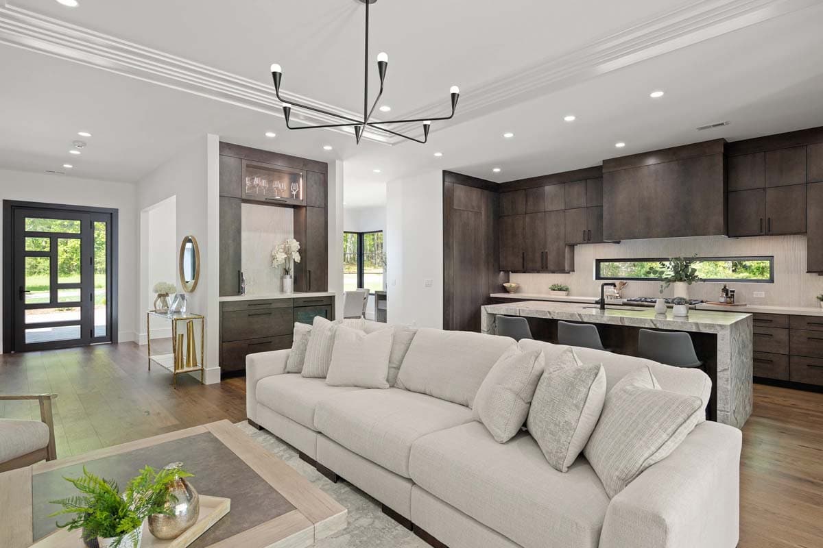 Open concept living area with a sectional sofa, kitchen island with bar seating, and a wet bar.