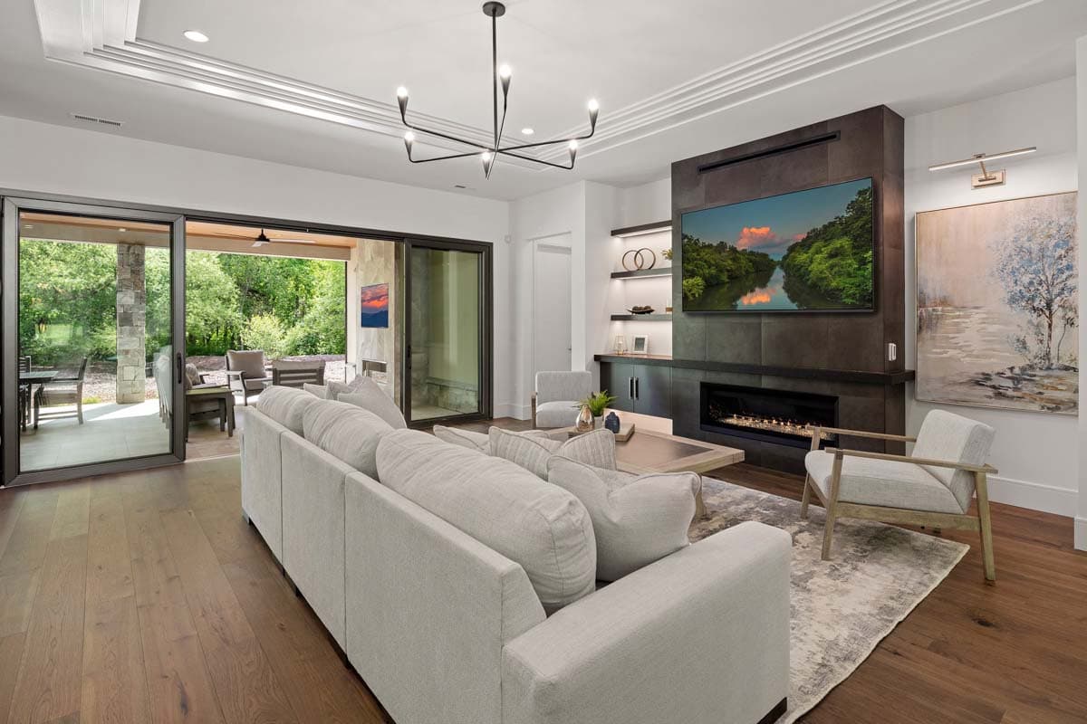 Living room with sectional sofa, fireplace, mounted TV, and large sliding glass doors leading to an outdoor patio.