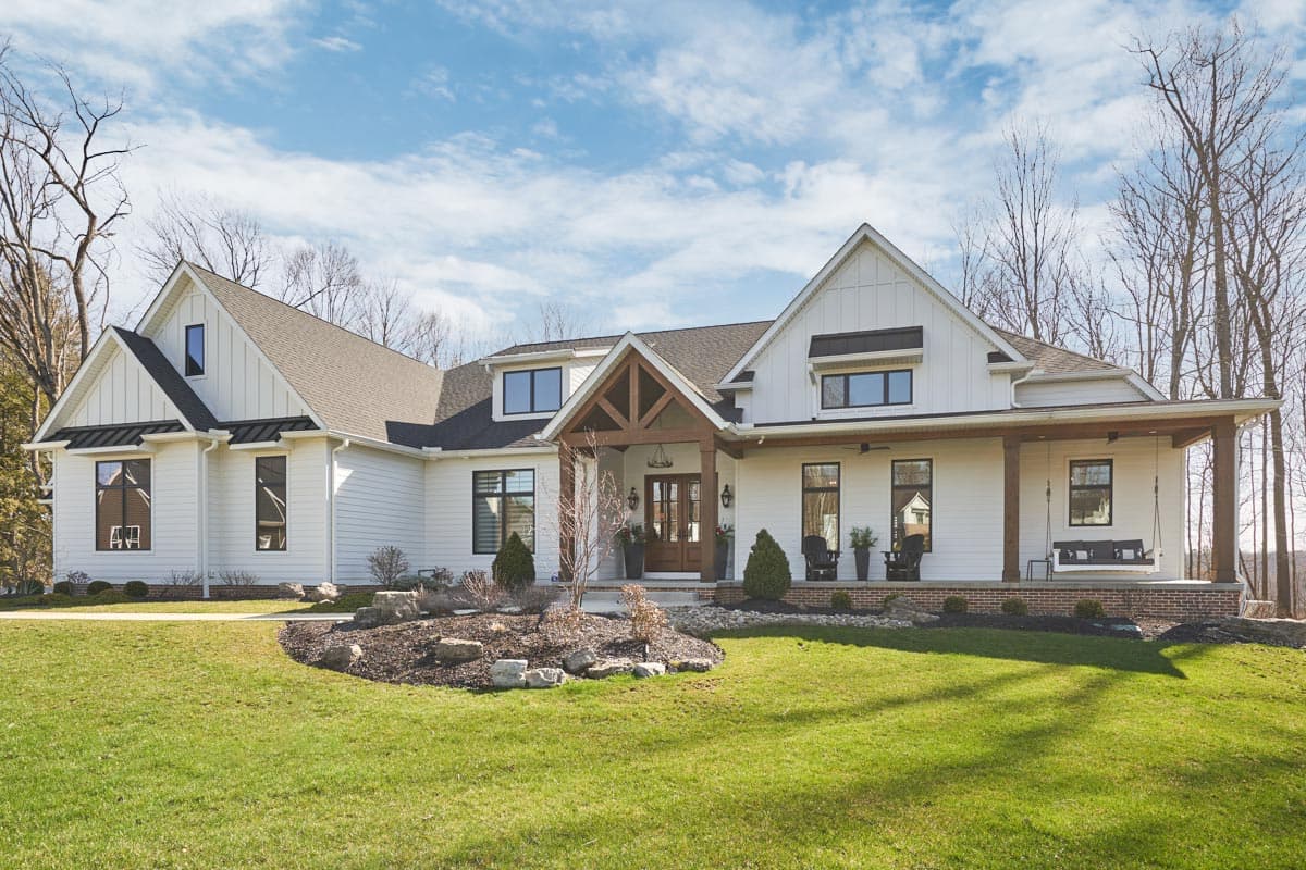 Modern Farmhouse house plan exterior with gabled dormers, a covered front porch with timber supports, and white board and batten siding.