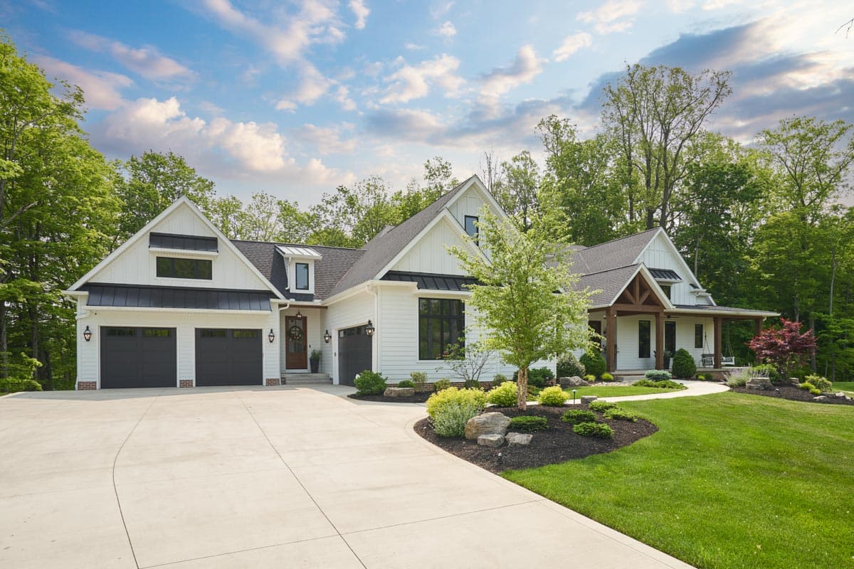 Modern Farmhouse style house plan exterior with a three-car garage, gables, dormers, and a covered porch with timber beams.