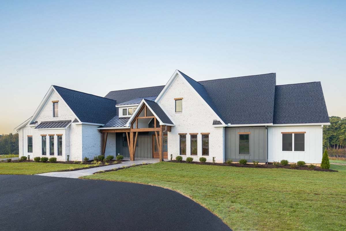 Modern Farmhouse house plan exterior with white brick, gabled rooflines, prominent wooden beams, and metal roof accents.