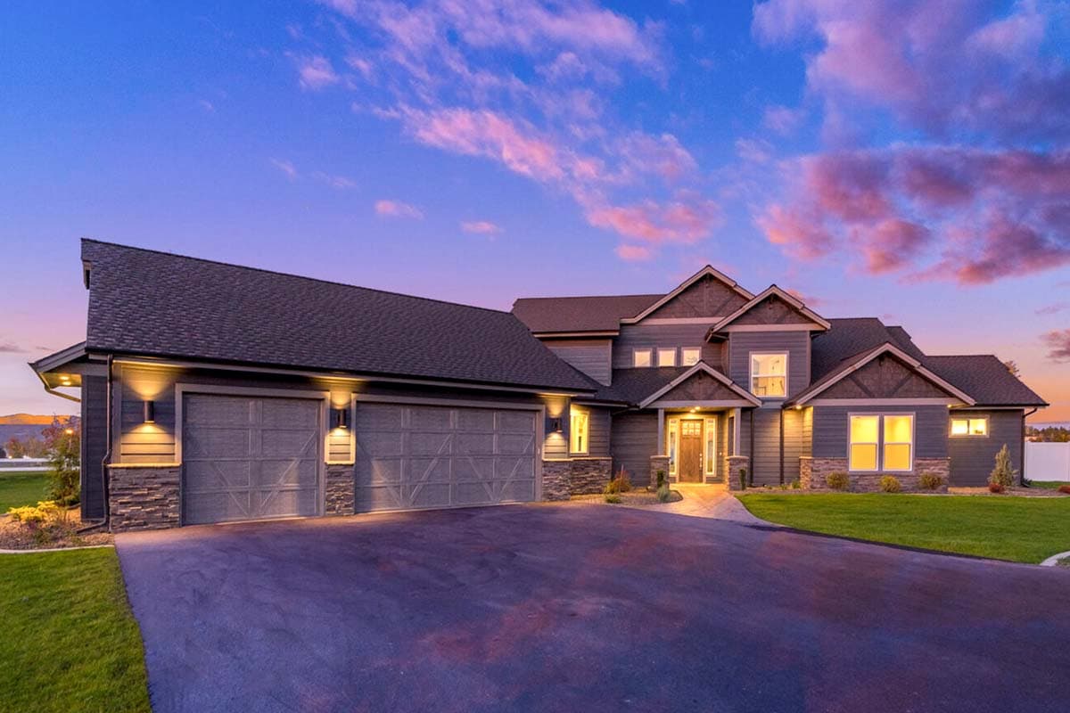House plan exterior featuring a two-story Craftsman style home with a front-facing garage, gables, and stone accents on the facade.