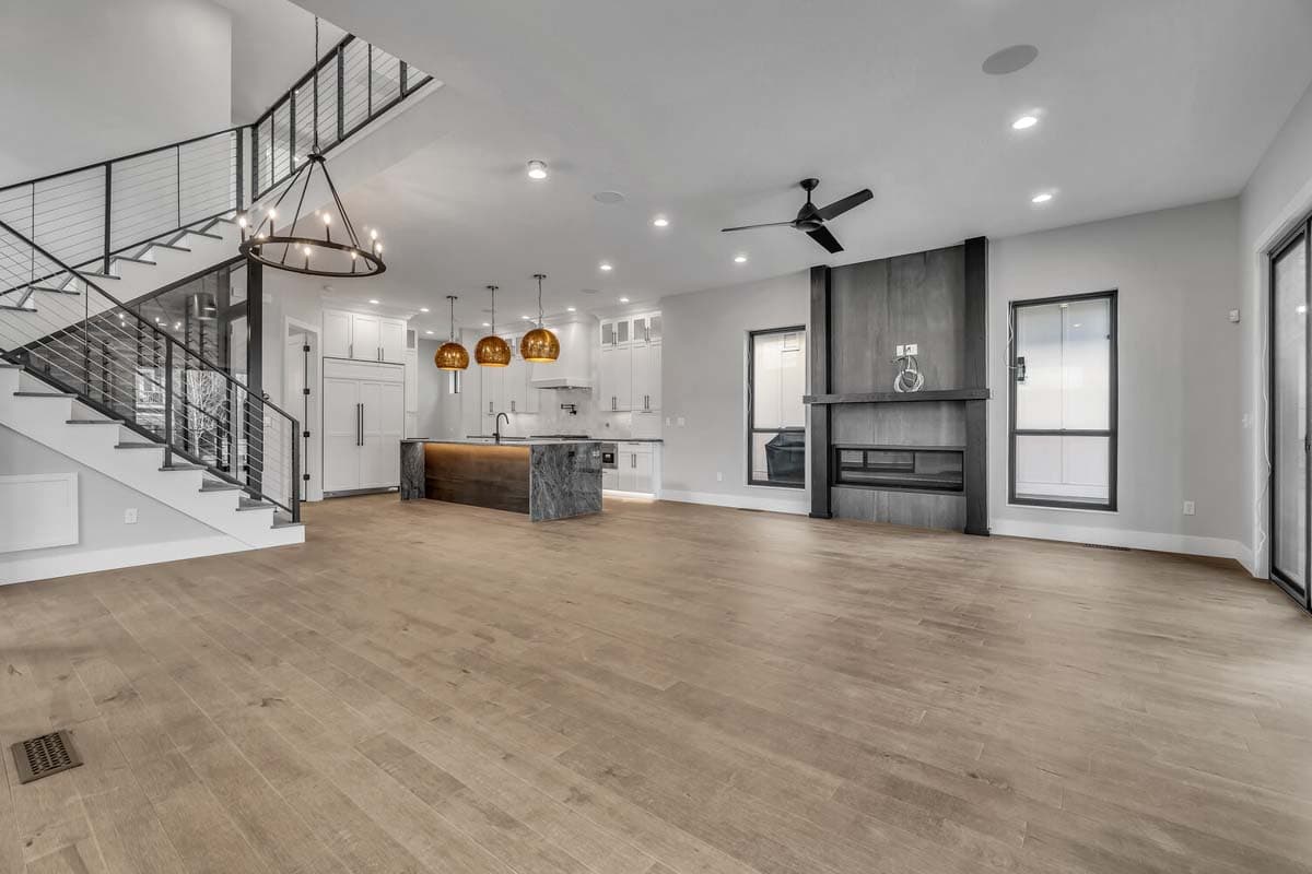 Open-concept living area with a floating staircase, modern fireplace, and kitchen island.