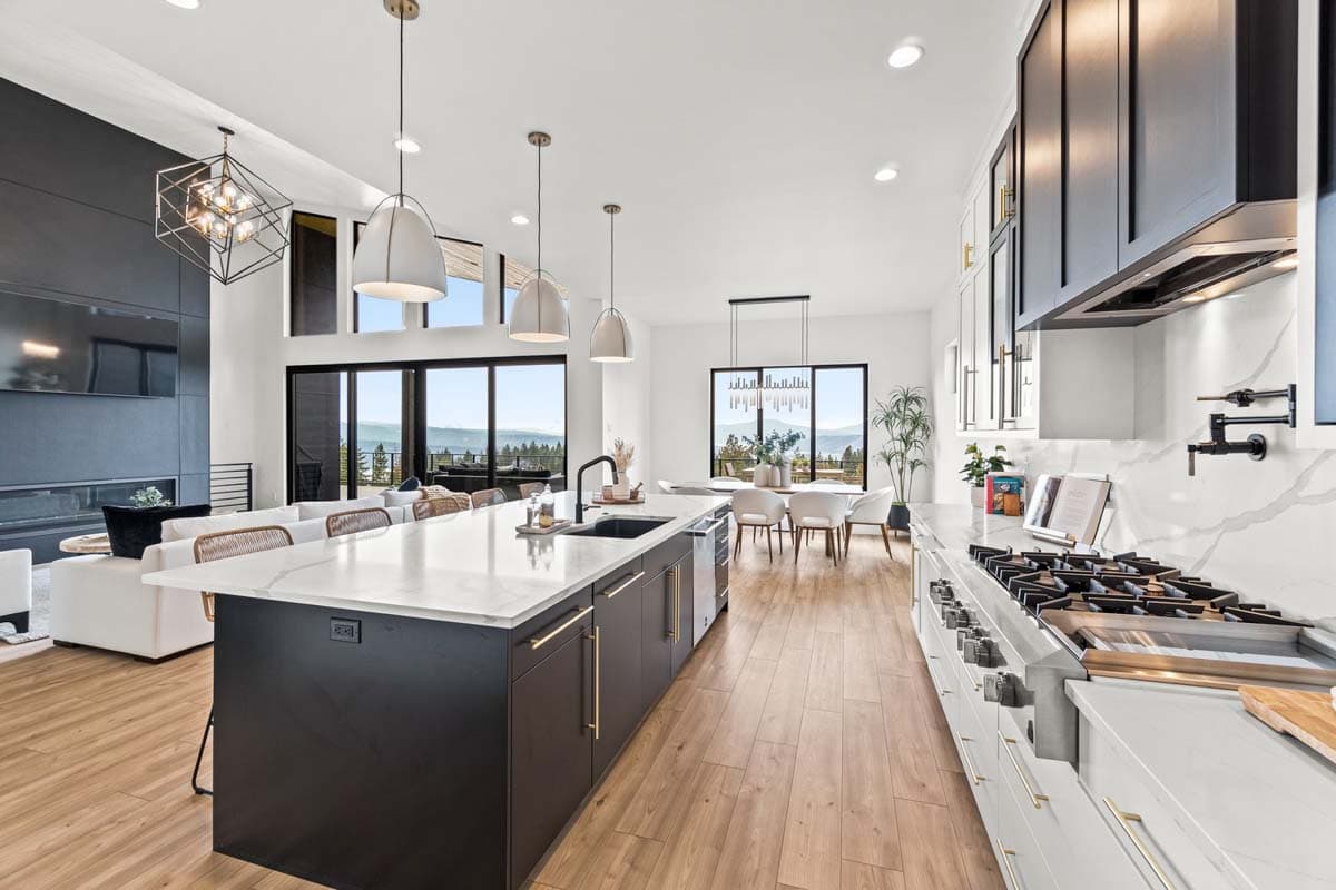 Modern great room with large island, fireplace, and expansive windows overlooking a mountain view.