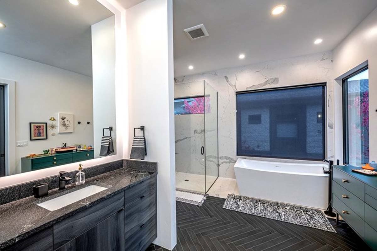 Modern bathroom with freestanding tub, glass-enclosed shower, double vanity with dark wood cabinets, and marble tile.