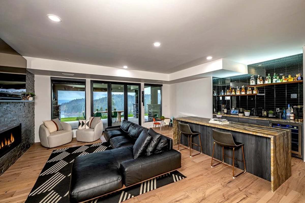 Living room with stone fireplace, sectional sofa, and full bar with island seating.