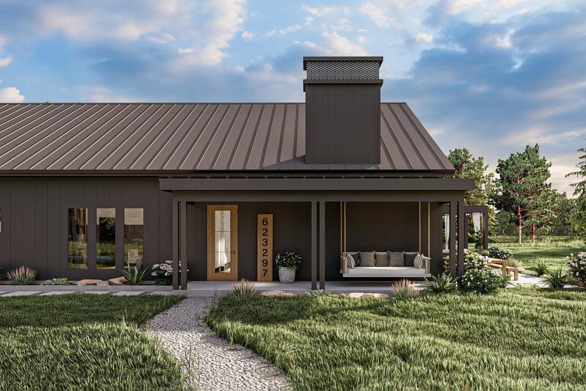Modern dark grey house with covered porch, swing, and address sign. A stone path leads to the front door, with lush green grass and a cloudy sky.
