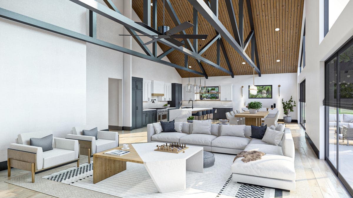 Spacious, modern living room with high ceilings, exposed beams, and a view into the kitchen area. A large sectional, armchairs, and a chess set are present.