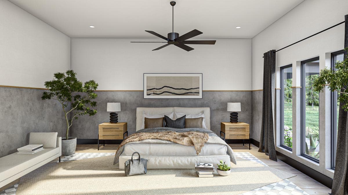 Modern bedroom interior with a large bed, artwork, and large windows with a view of greenery. A decorative ceiling fan is visible above the bed.