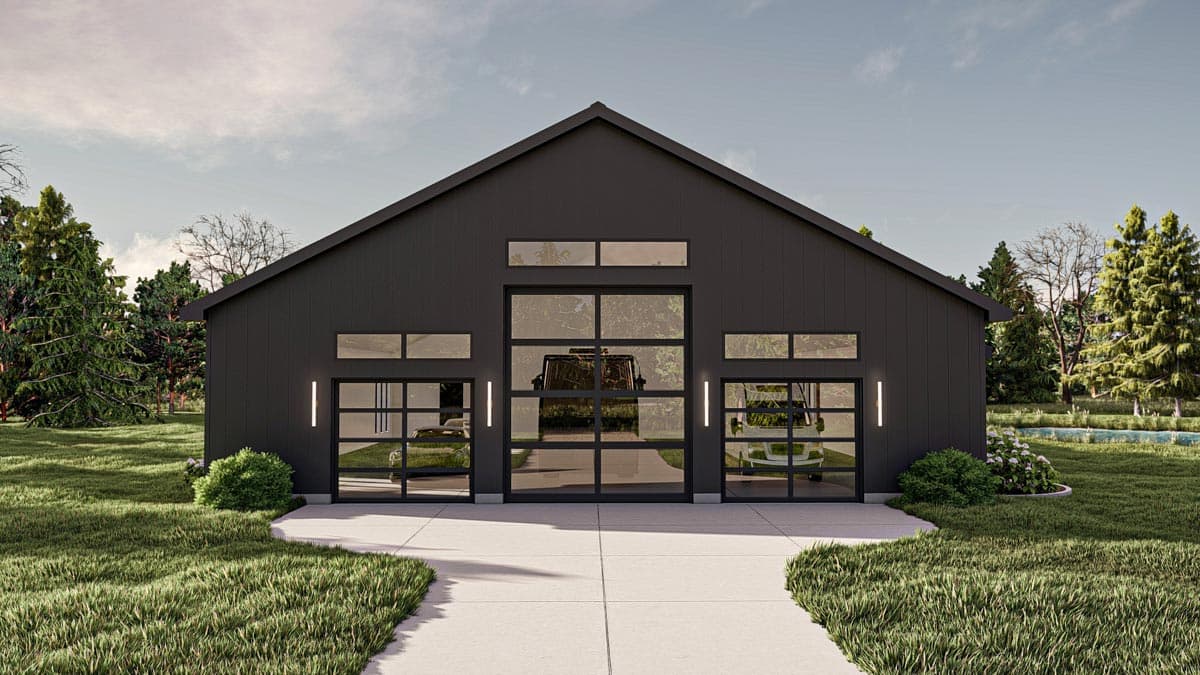 Modern black barn-style garage with glass doors reflecting vehicles inside. The building sits at the end of a concrete path, surrounded by trees.