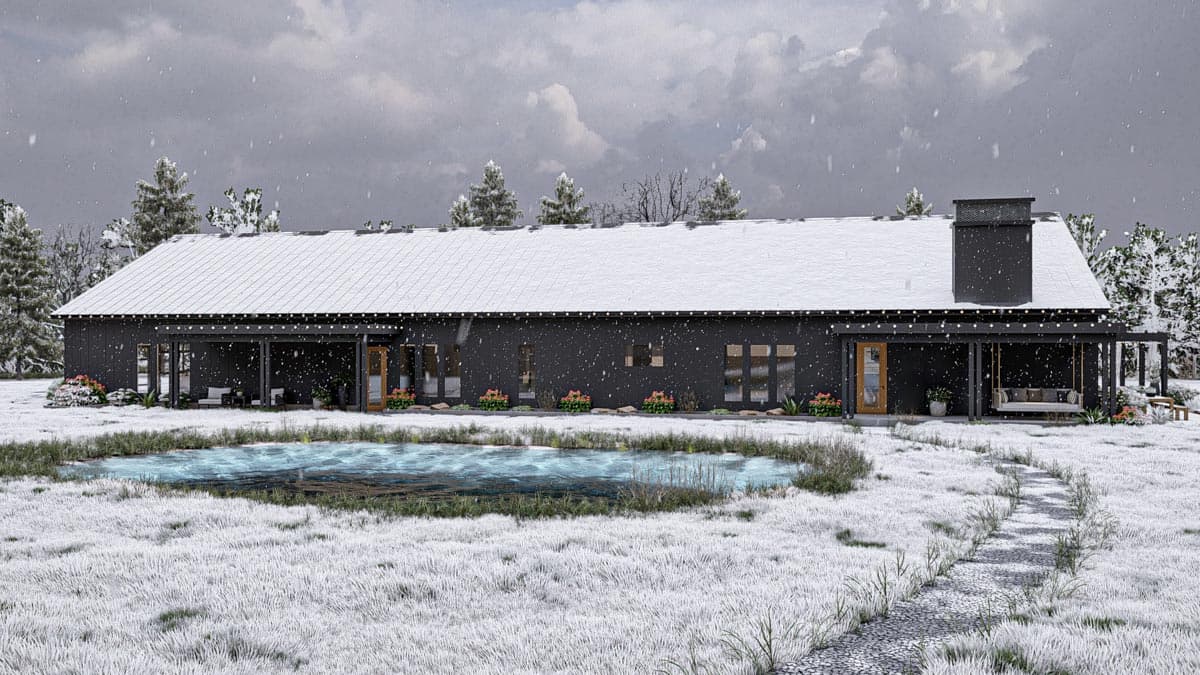A modern, black-sided house with a snow-covered roof and porch overlooks a pond. Snow falls gently on the winter landscape.