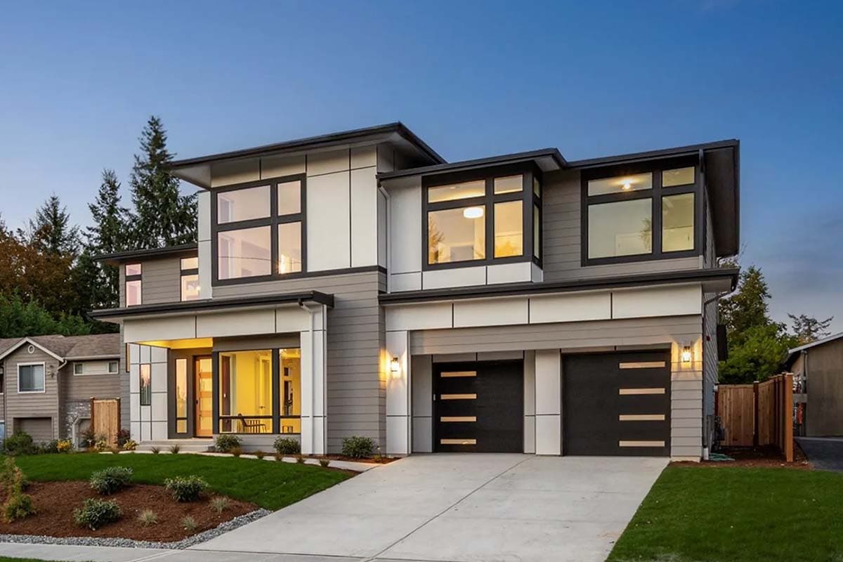 Modern house plan exterior with two-car garage, layered rooflines, and prominent geometric windows.