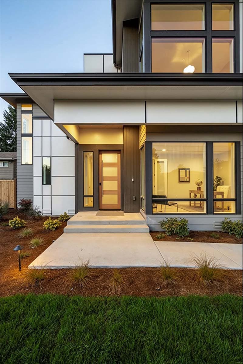 Modern house plan exterior with a multi-story design, glass entry door, and large corner windows.