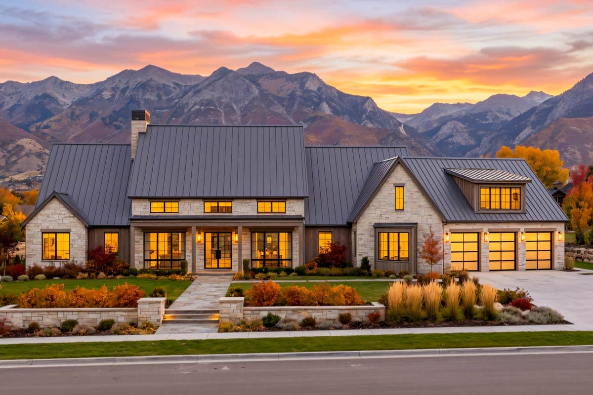 Modern Farmhouse exterior with stone and wood facade, metal roof, covered porch, and triple garage. House plan.
