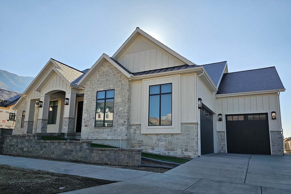House plan exterior of a single-story Modern Farmhouse with stone and board-and-batten siding, gabled roof, and a two-car garage.