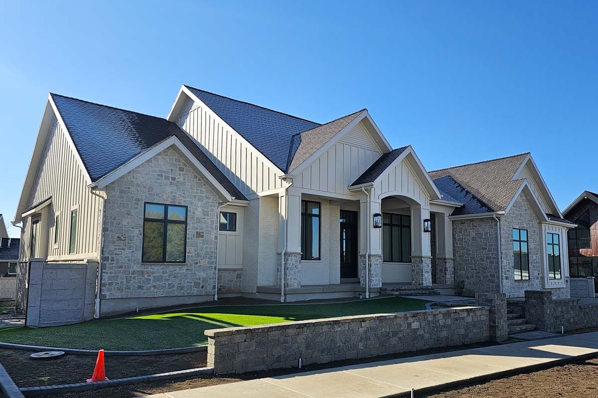 House plan exterior: Modern Farmhouse style, one story, with stone accents, board and batten siding, gables, and covered entryway.