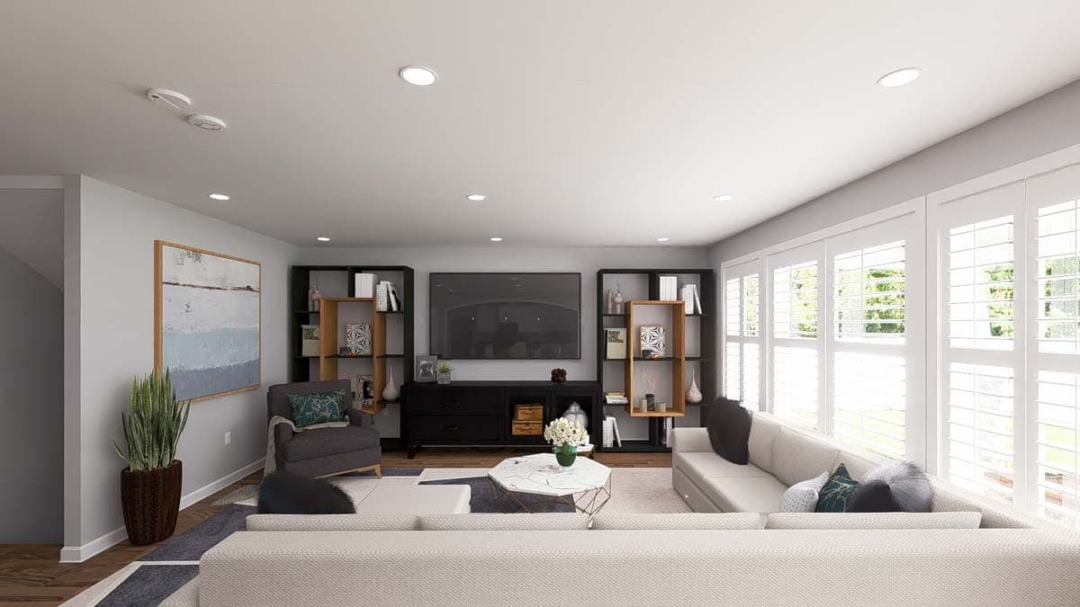 Living room interior with sectional sofa, entertainment center, bookshelves, armchair, and large plantation shutters.