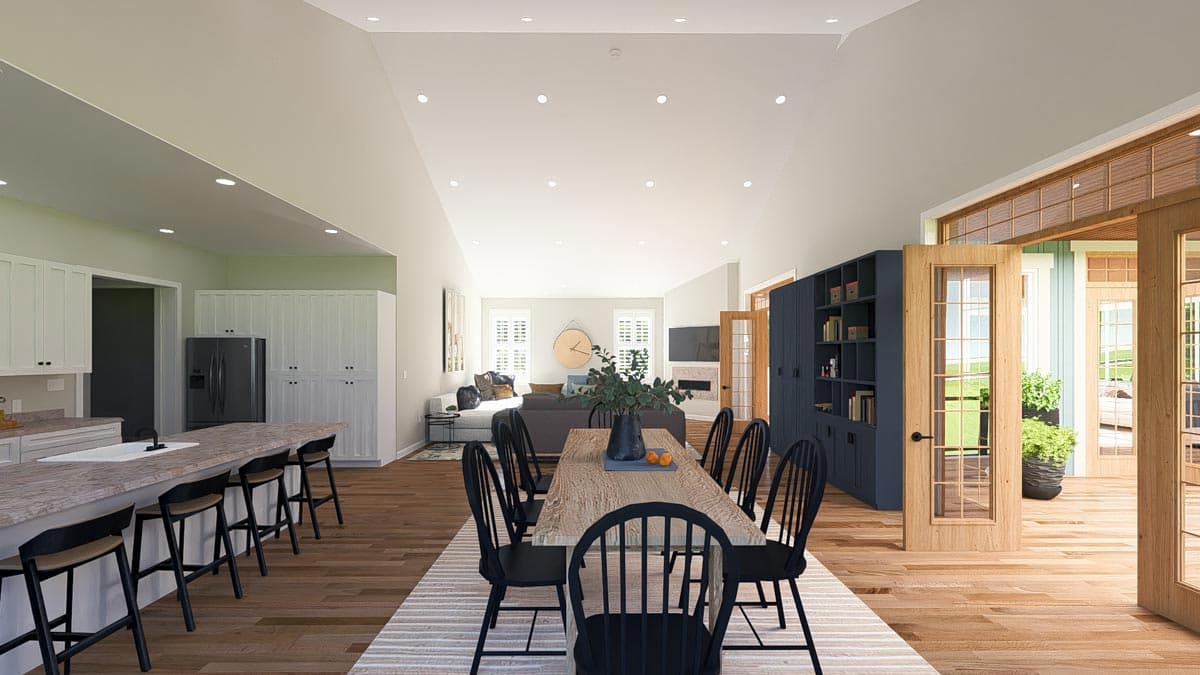 Open concept interior: kitchen with island, dining area with wood table, and living room with fireplace and vaulted ceiling.
