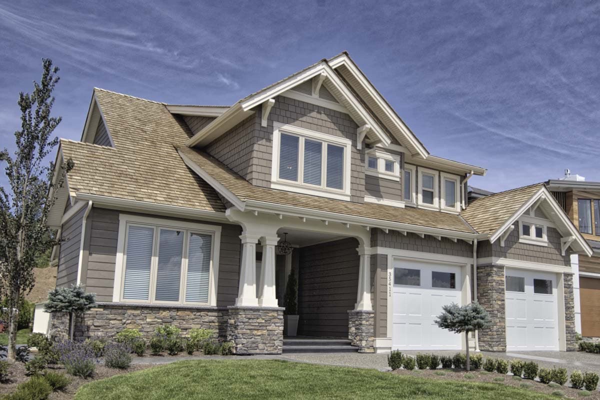 Craftsman style house plan exterior, two stories, stone base, covered porch with columns, and a two-car garage.