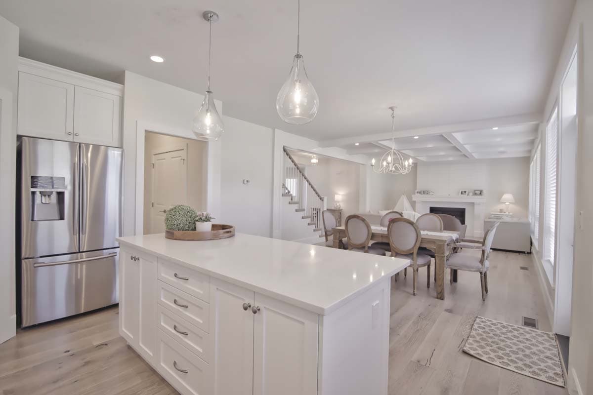Open-concept living space with kitchen island, dining area, great room with fireplace, and coffered ceiling.