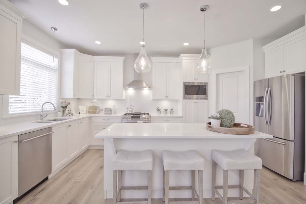 Contemporary kitchen with white cabinetry, island, stainless steel appliances, and pendant lighting.