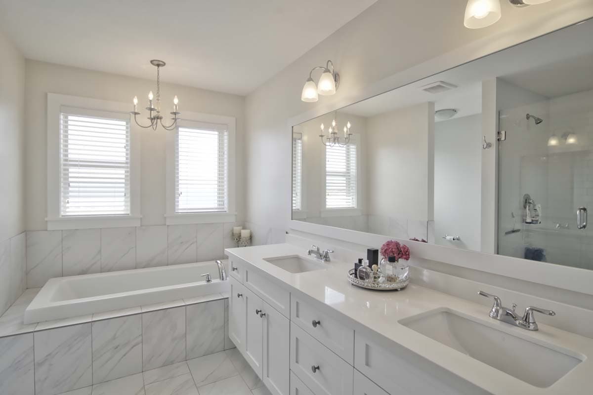Bathroom interior with soaking tub, double vanity, large mirror, and glass-enclosed shower.