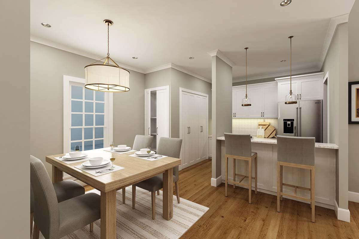 Dining area with table and chairs adjacent to kitchen with island, bar stools, and stainless steel refrigerator.