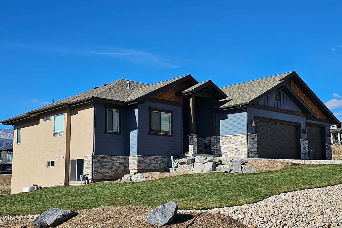 House plan exterior: two-story modern home with stucco and lap siding, stone accents, gables, and a three-car garage.