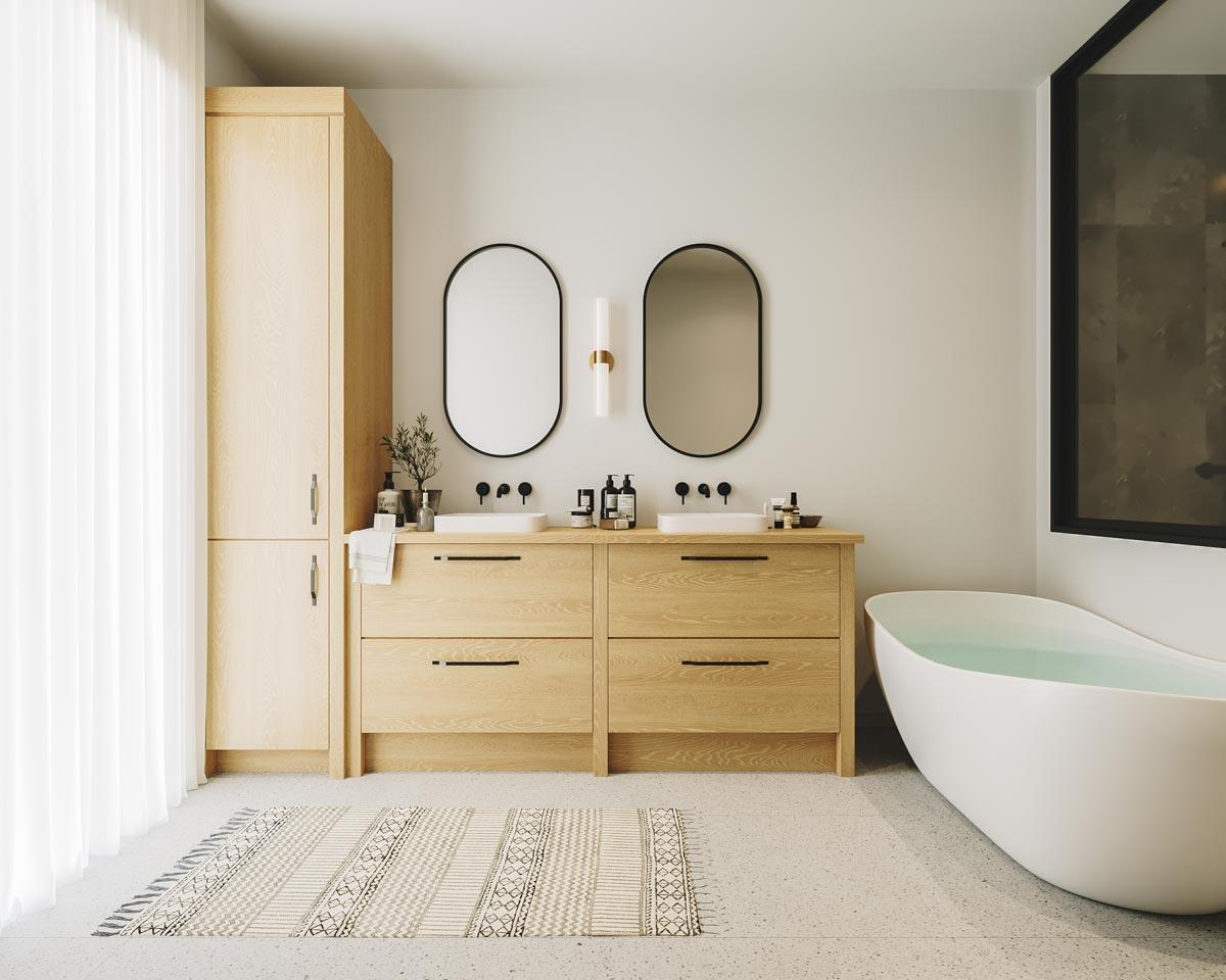 A modern bathroom features light wood cabinetry, oval mirrors, and a freestanding tub filled with water, creating a spa-like atmosphere.