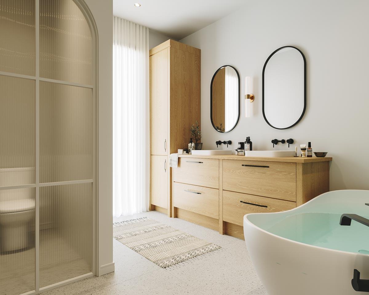 Modern bathroom with a wooden vanity, two oval mirrors, and a freestanding tub. The room has neutral tones with a textured glass door.