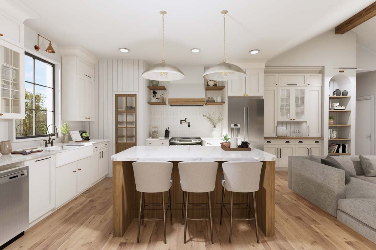 Kitchen interior with island seating, farmhouse sink, stainless steel appliances, and adjacent living area.