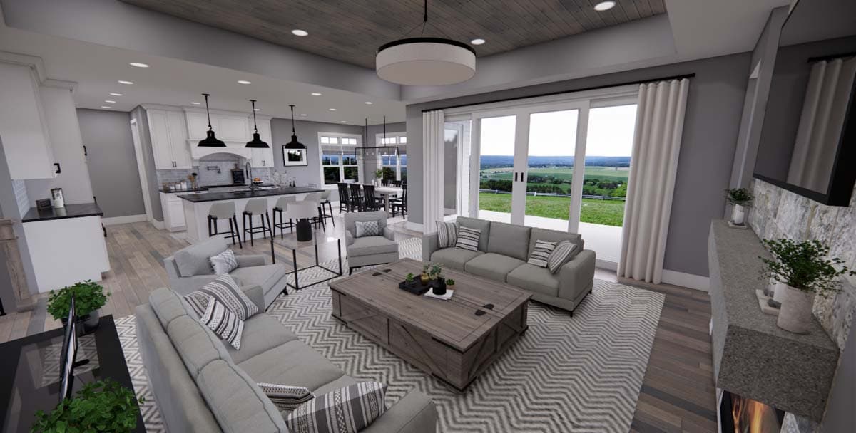 Open-concept living area with kitchen island, great room fireplace, and dining area. Vaulted wood ceiling and large sliding doors.