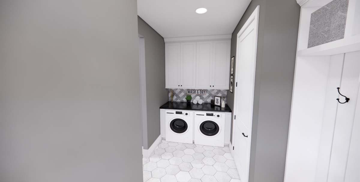 Laundry room with white washer and dryer, black countertop, white cabinets, and hexagonal floor tiles.
