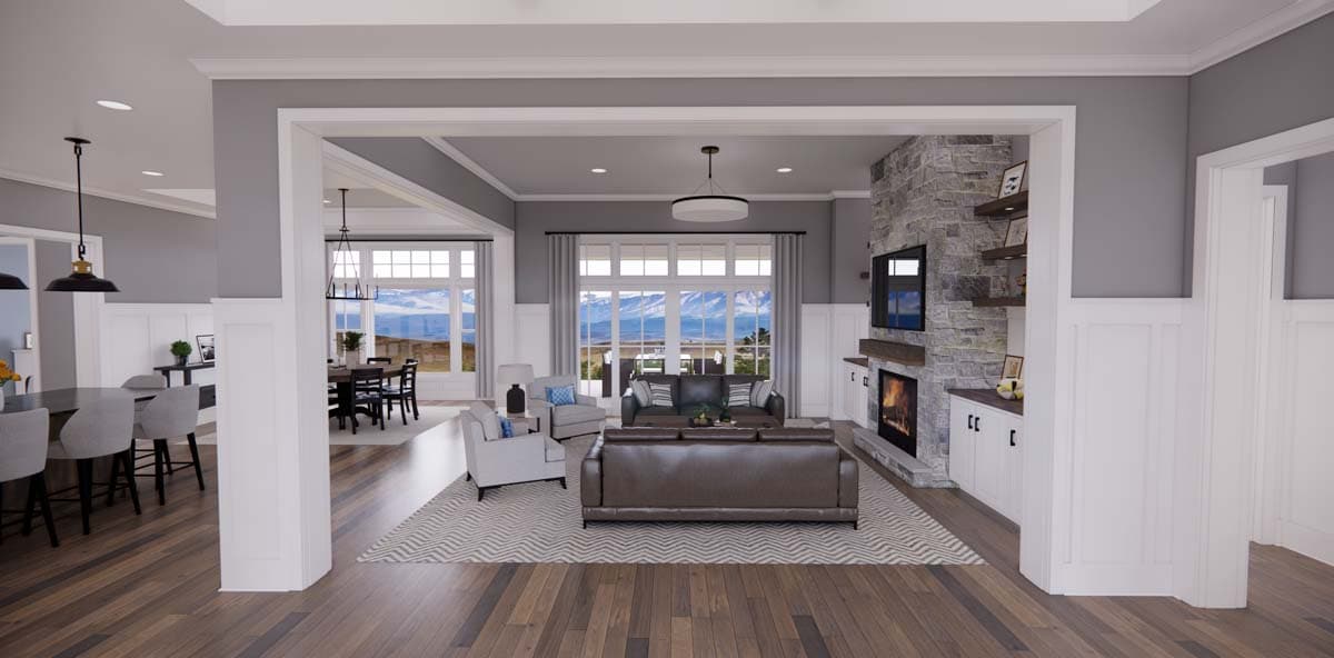 Great room with stone fireplace, large windows, and open layout connecting to dining and kitchen areas.